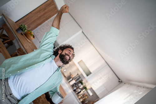 Konstfotografi Happy man stretching in kitchen, enjoying energized morning