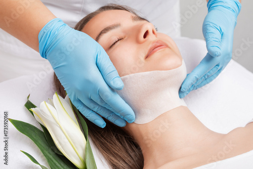 Slika na platnu A cosmetologist makes a fat-burning mask for a double chin