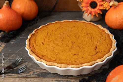 pumpkin pie oder Kuchen aus Kürbis angerichtet auf einem Tisch aus Holz und herbstlich oranger Dekoration