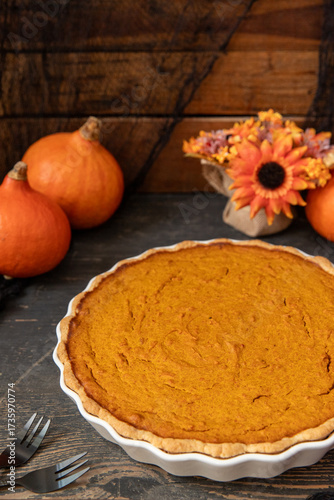 pumpkin pie oder Kuchen aus Kürbis angerichtet auf einem Tisch aus Holz und herbstlich oranger Dekoration