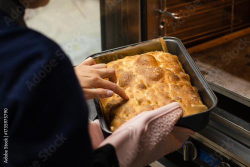 Woman checking freshly baked homemade bread with her finger near the oven