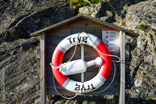 Close-up of lifebuoy station on rocky shore.