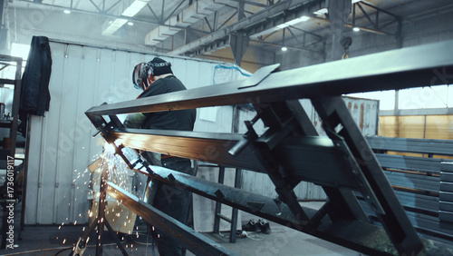 Skilled industrial worker wearing protective gear while welding metal components, creating sparks and showcasing manufacturing processes and precision in a factory environment