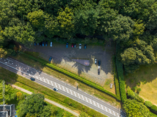 Wallpaper Mural Aerial view of parking lot beside forest, with aligned vehicles, central triangular monument, hedges, and road markings blending geometry and natural surroundings. Torontodigital.ca
