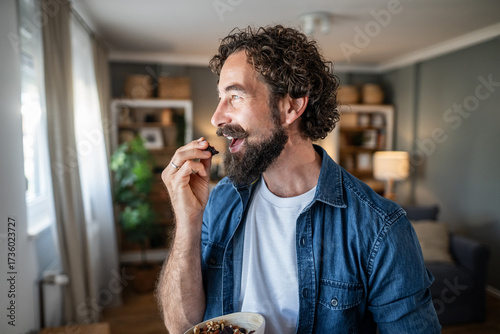Fényképezés Man enjoying healthy dried fruit and nut snack at home