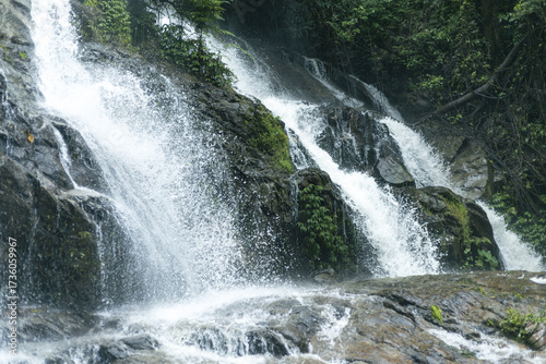 Impressive waterfall demonstrates raw power of nature, where water flows and cascades over dark rock. forest vibrant green creates natural stream, offering truly refreshing and peaceful outdoor