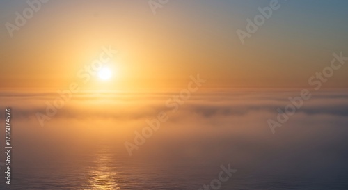 広がる水平線に燦然と輝く黄金色の夕日が立ち込める霧を優しく染め上げ水面にきらめく光の帯を創り出す幻想的で心癒される絶景美しい自然の彩り. AI Generated