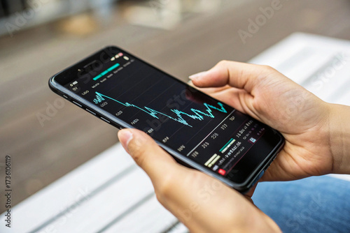 Close-up of Hands Holding Smartphone Outdoors, Analyzing Live Financial Chart and Cryptocurrency or Stock Market Data on a Mobile Trading App