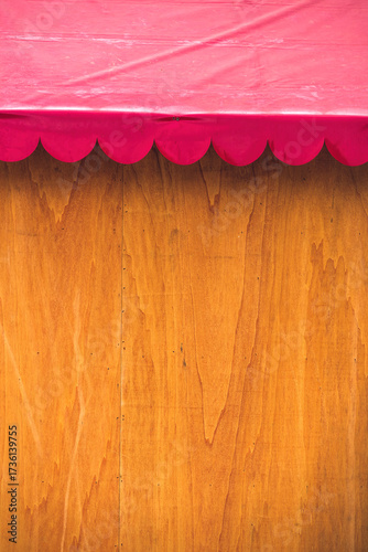 Bright pink awning shades wooden wall in sunny outdoor market setting
