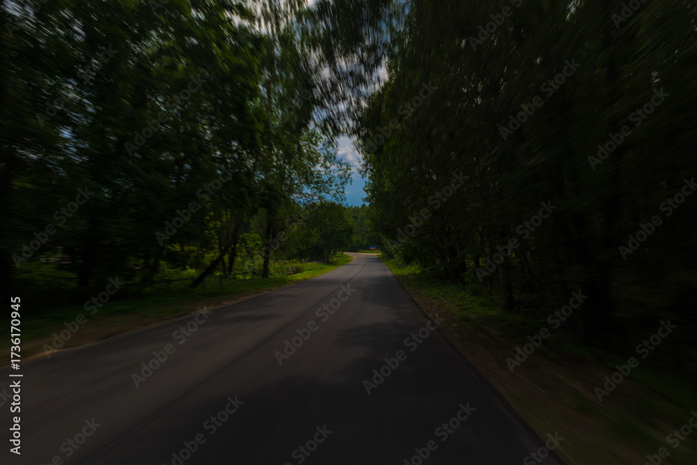 Obraz premium The effect of speed on the road and blurred objects. View of the road on a sunny summer day.