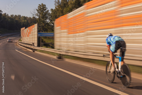 The effect of speed on the road and blurred. View of the road on a summer day. Cyclist riding along the road