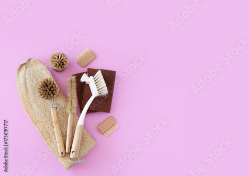 Top view cleaning supplies, bamboo brushes and natural sponges, zero waste household concept on a pink background