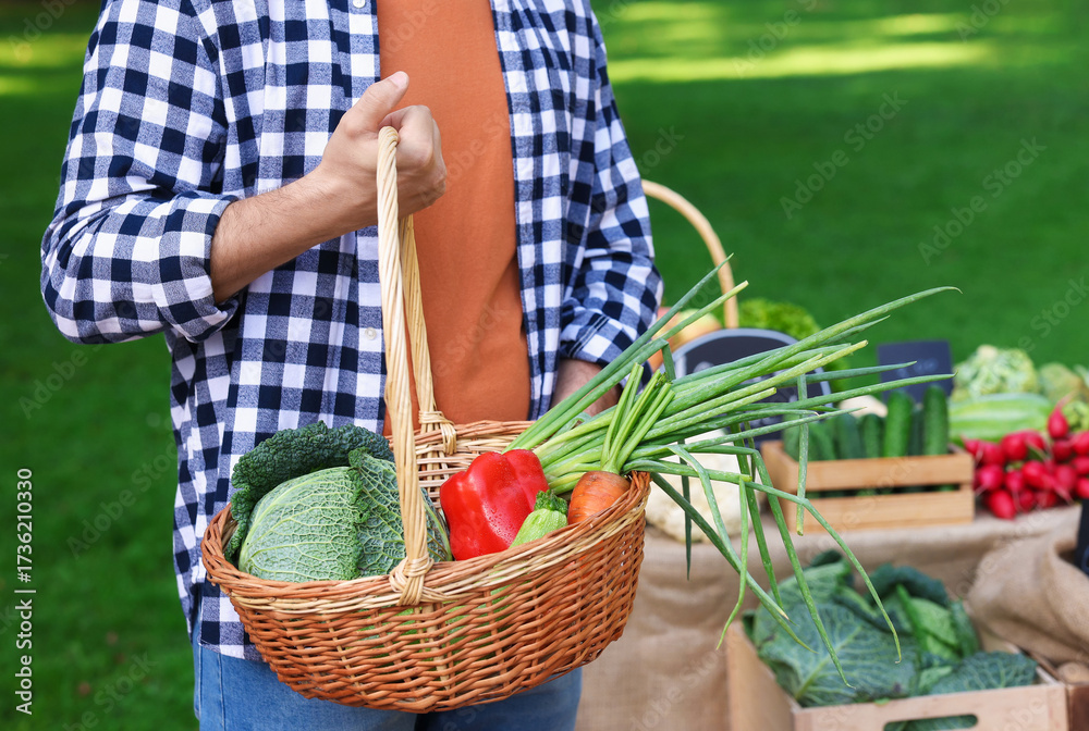 Fototapeta premium Man with different vegetables in wicker basket at farmer's market, closeup