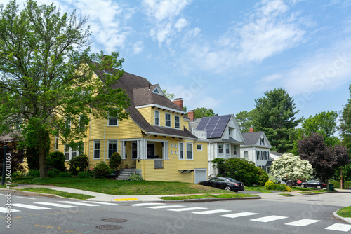 Picturesque residential street featuring a charming yellow house and beautifully landscaped neighboring homes in Newton, Massachusetts, USA
