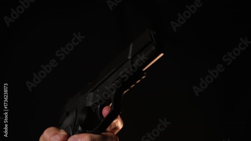 Man's Hand Wiping a Firearm, Dark Background