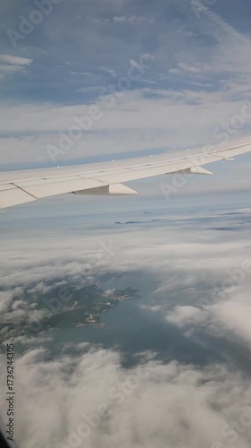 view of wing from plane window. Airplane flying above clouds. Airplane fly over snowy mountain hills. vertical video
