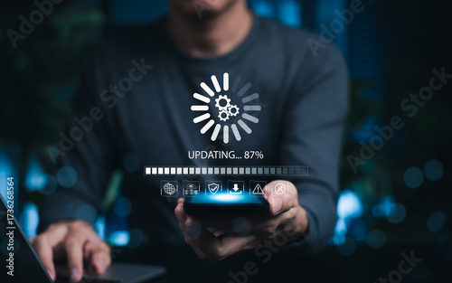 Software Update and System Upgrade Concept. Person holding phone while using laptop with software update progress interface and security, technology maintenance, application upgrades, system security.