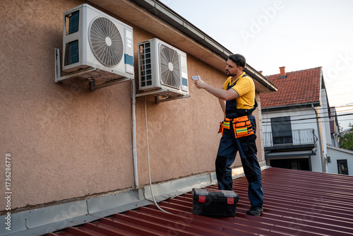 Professional technician repairs air conditioning units on a residential rooftop in the evening light