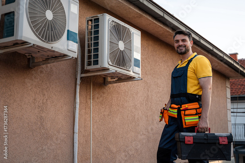 Man wearing work uniform fixing air conditioning units on a building in sunny weather