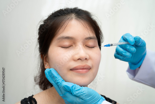 Asian woman receiving plastic surgery shape of nose performed on face.