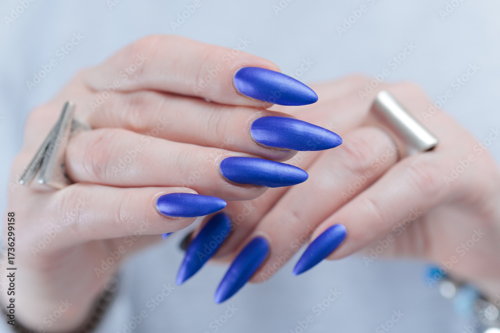 Fototapeta premium Woman's beautiful hand with long nails and blue nail polish