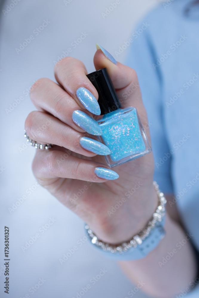 Fototapeta premium Female hand with long nails and bright light blue and silver manicure 