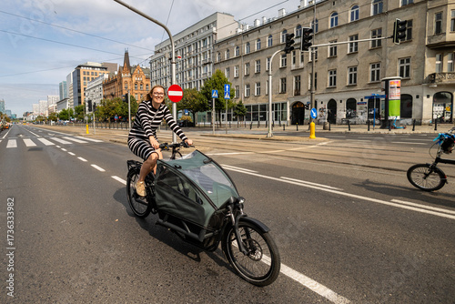Young woman riding a cargo bike in the city on a sunny day
