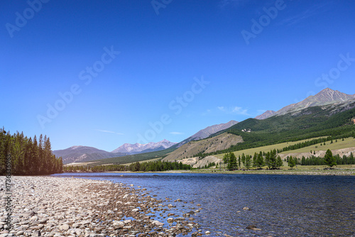 Summer adventure landscape with fast mountain river, forest to tundra slopes, and open sky