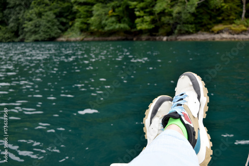 feet in sneakers on the background of a lake, river