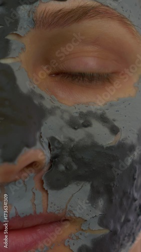 Close up of woman face with black clay charcoal mask. Vertical video
