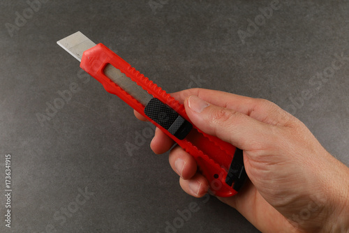 Hand holding red utility knife with metallic blade