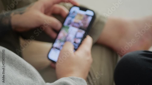 Man using his smartphone to scroll through an Instagram feed, browsing posts and videos. Close-up captures social media interaction, digital engagement, and modern mobile lifestyle.