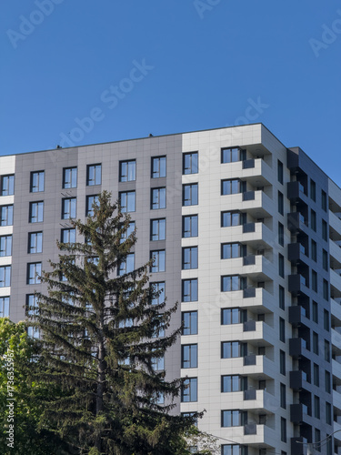 Modern residential building facade with tall tree