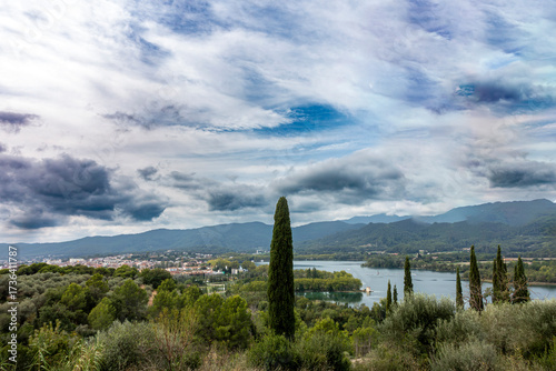 Panoramic Landscape of Banyoles Lake and Town Gerona Spain Famous Olympic Rowing Site with Cypress Trees and Dramatic Sky