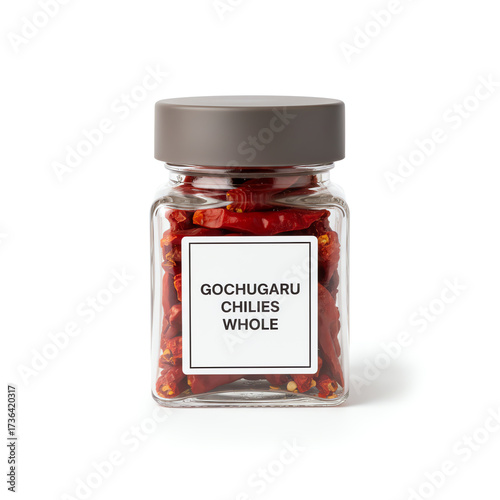 A glass jar of gochugaru chillies whole on white background