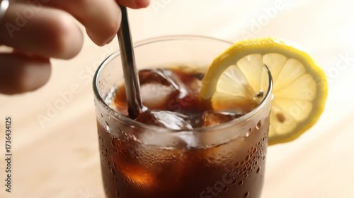 Refreshing Iced Coffee: Stirring with Straw and Lemon Slice Close-Up