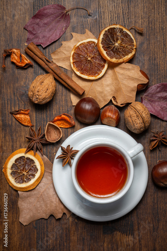 Aerial view of a cup of tea on a table with nuts and autumn leaves, vertical, with copy space