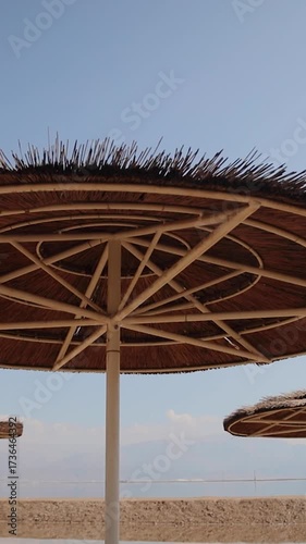 View from under a straw umbrella to the clear blue sky, on a sandy beach near Dead Sea, beach holidays in Israel. Vertical video