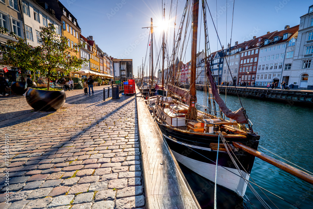 Obraz premium Vessel moored on famous Nyhavn canal with colorful buildings in the morning. Copenhagen main tourist attraction, Scandinavian coastal city, Denmark.