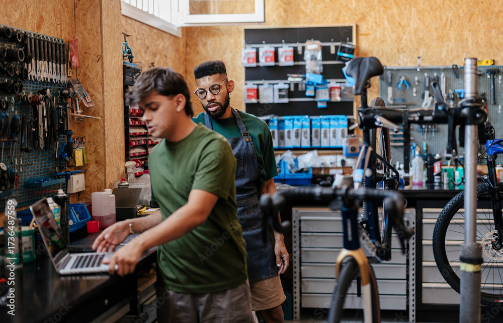 Obraz premium Bicycle shop mechanics using laptop for business management