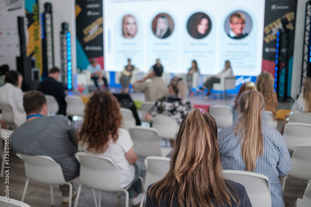 custom made wallpaper toronto digitalAudience attends conference panel discussion with speakers on stage in modern venue, bright screens, blue lighting