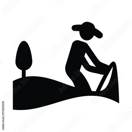 Silhouette of a person wearing a hat rowing a boat on a calm body of water with a tree nearby