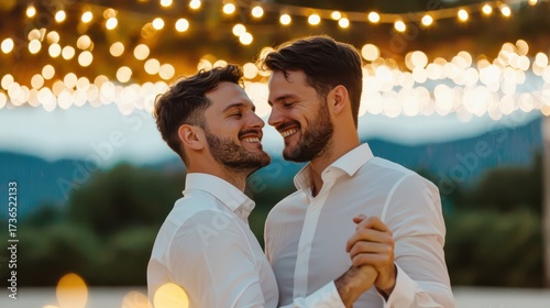 Two smiling men dance together under twinkling lights, capturing a joyful moment of love and connection in a serene outdoor setting.
