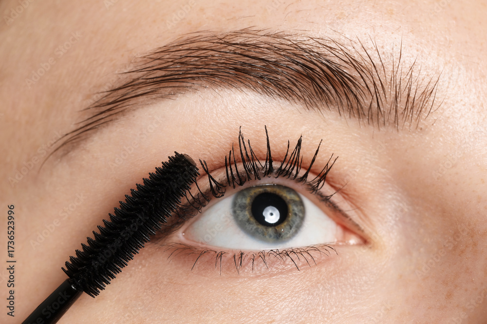 Obraz premium Woman applying mascara onto her eyelashes, closeup