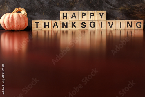 Wooden Happy Thanksgiving letters with pumpkin reflection. Concept of email marketing, holiday promotion and seasonal celebration.