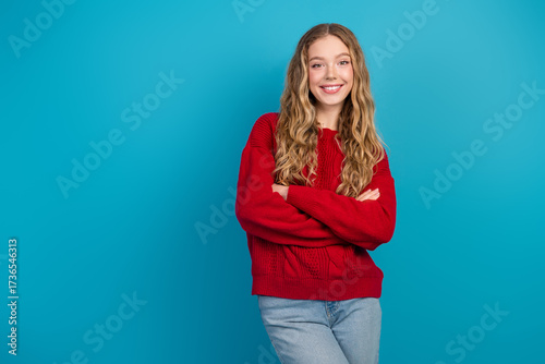 Tableau sur toile Adorable young woman in red sweater posing confidently against blue background w