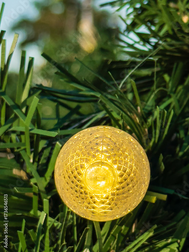 Closeup of a yellow lightbulb glowing on an artificial Christmas tree in December at a suburban mall in southwest Florida