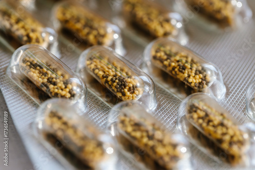 Blister pack of transparent capsules filled with herbal granules. Concept of dietary supplements, vitamins, natural medicine, pharmaceutical products and healthcare industry background
