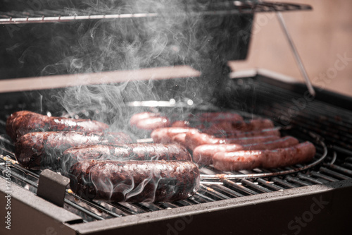 Close-up of steaming and tasty blood sausage and white sausages, cooked over charcoal on the barbecue. Dark edition
