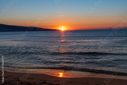 Stunning sunset over the calm sea, with warm golden and orange hues reflecting on the water. The peaceful coastal scene evokes relaxation, romance, and natural beauty, perfect for themes of travel,